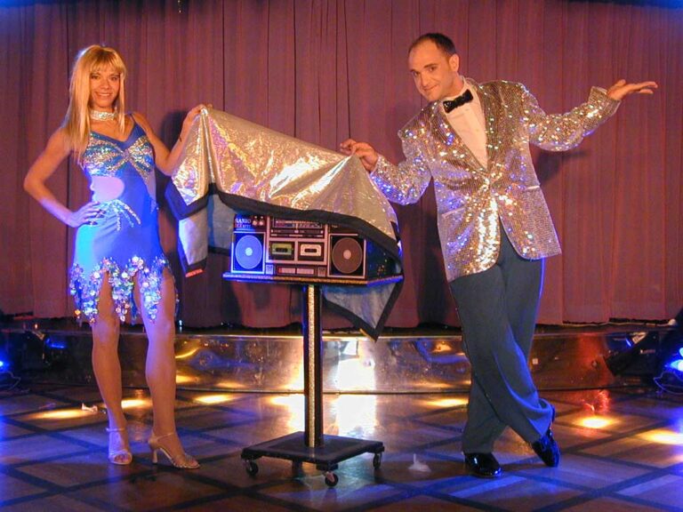 Talented stage magician in Hong Kong and his assistant performing a great show ,they are covering the radio between them with a sliver cloth at a festival function