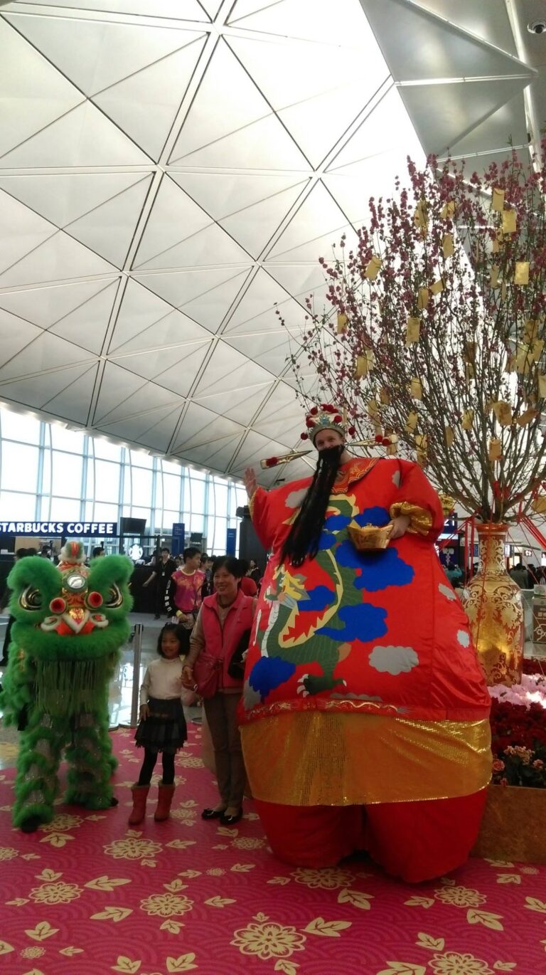 HK stilt-walker in giant inflatable Choi Sun costume at airport Chinese New Year event