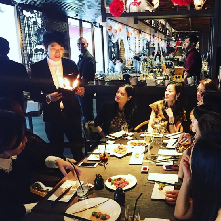 Magician performing roving fire magic to ladies at a Hong Kong restaurant