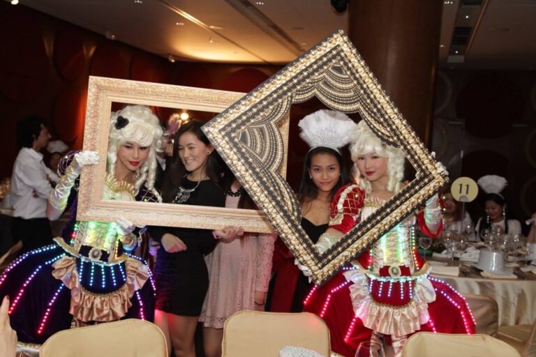 Two pretty girls wearing courtesan style costume with LEDs and having pictures taken with large photos frames