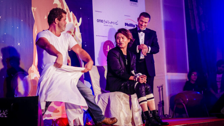 HK magician performing stage escape magic , and one of the audience helper is going to cover a white cloth at a corporate annual dinner