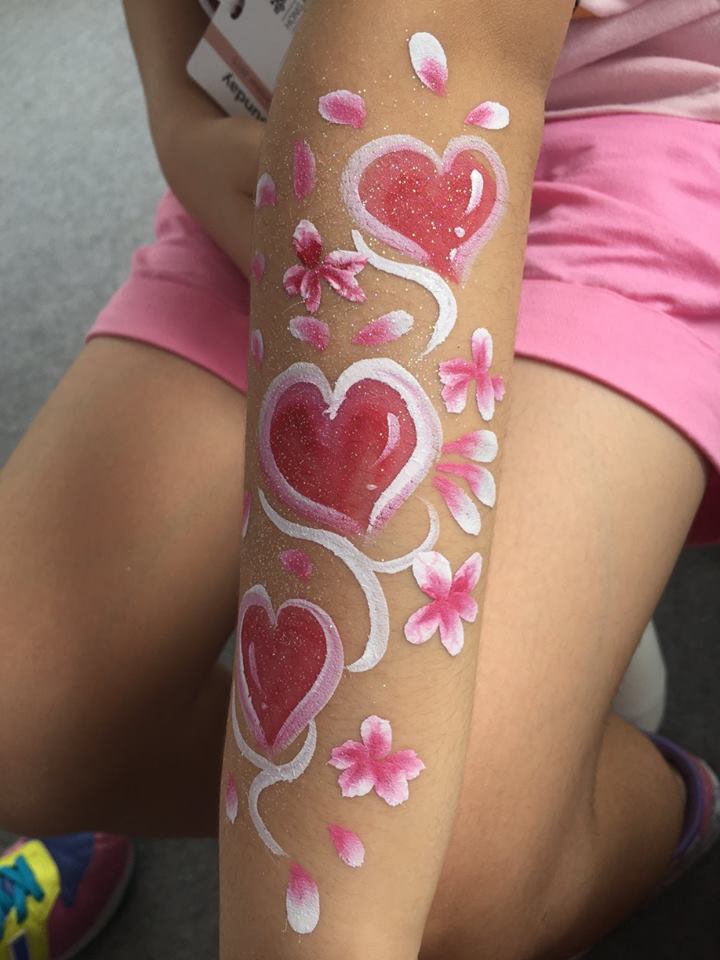 Face painter draw a Heart and flower hand paint with red , white and pink at a Hong Kong corporate event