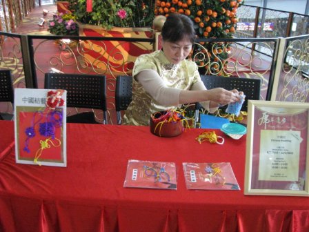 Hong Kong Professional artist in Chinese costume making Chinese Knot giveaway on site at a corporate Chinese new year event