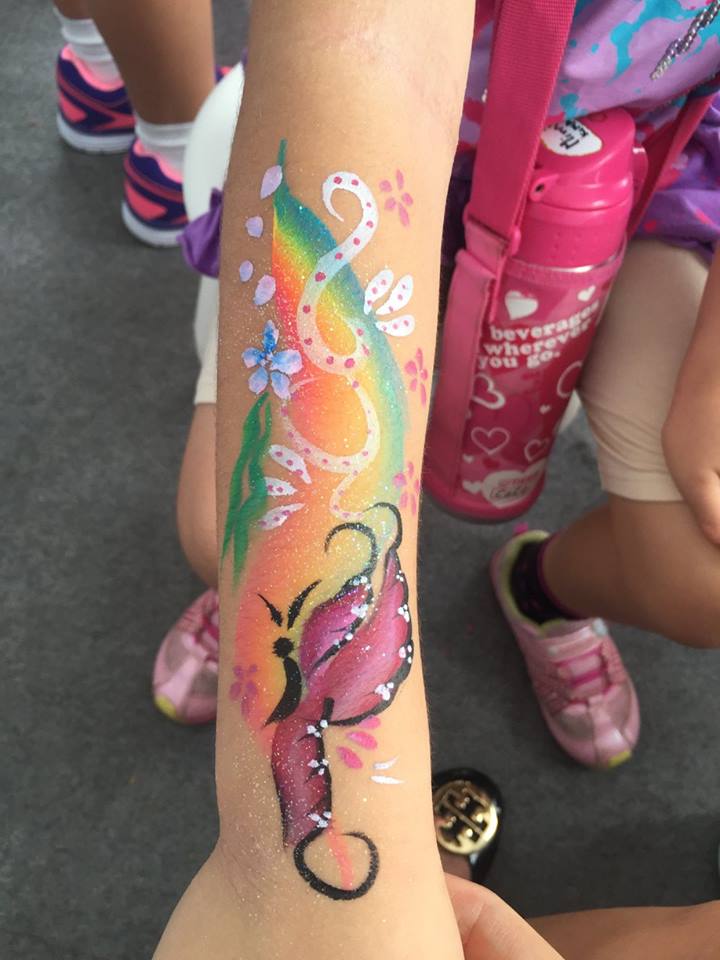 Hong Kong face painter draw a rainbow and butterfly painting on a children hand at a party