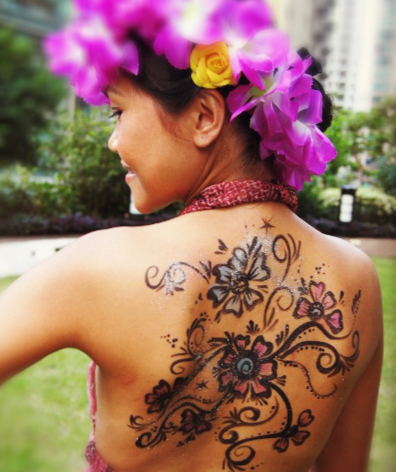 Hong Kong face painter draw a fancy flowers painting on a lady back who wearing a flower rings on head at a festive event