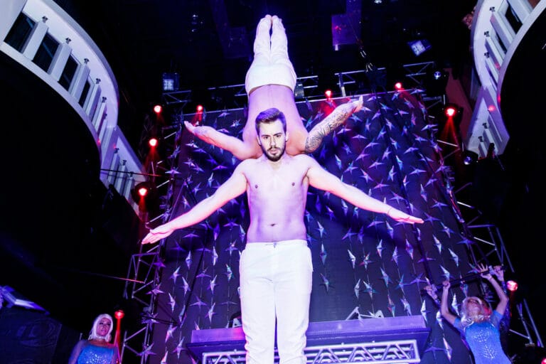 Two adage performers performing duo act at a corporate club event,one of the Performer upside down and holding by other performer with his shoulder only
