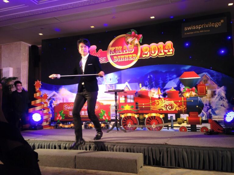 Magician performing stage magic with rope in front of a train backdrop at Hong Kong Swiss Privilege Christmas Dinner