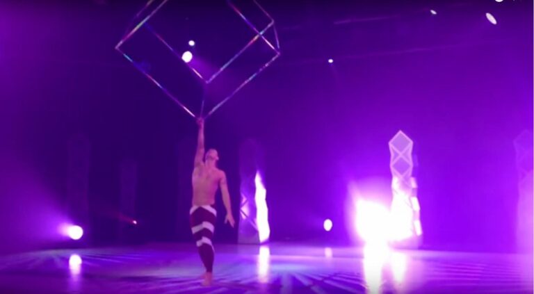 Acrobat spinning a giant steel cube above his head