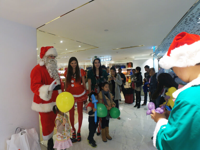 Santa performer with Santa girl and Elf models having a picture with three little kids who holding balloons at a Xmas event in Hong Kong