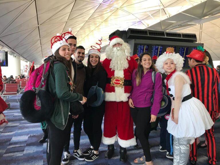 Santa standing with departure guests at HKIA and dancers