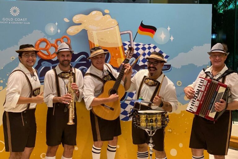 Band members jolly standing in front of a backdrop for oktoberfest for goald coast in tuen mum, hong kong