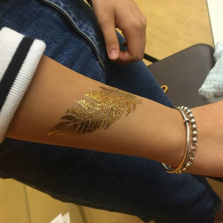 A guest choose a leaf shape gold tattoo on her hand at a school fun day event