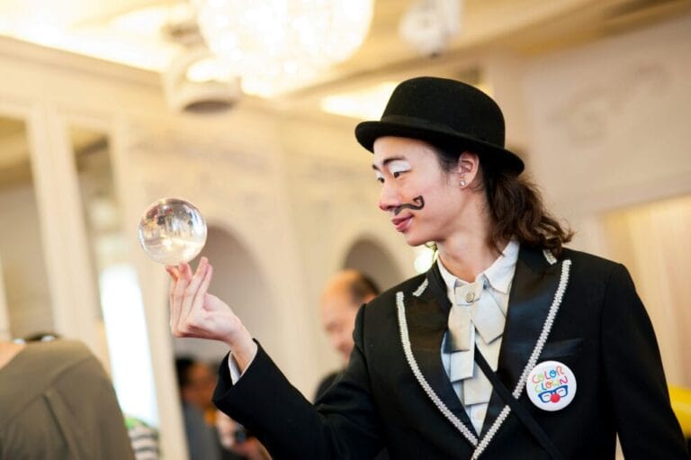 Contact juggler in HK wearing clown make up and costume performing with a crystal ball at a annual dinner