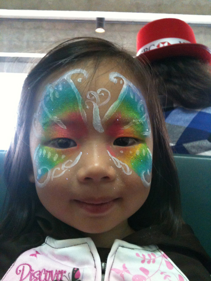 A Facepainter designed a rainbow butterfly face painter a a girl at the Hong Kong HSBC Xmas function.