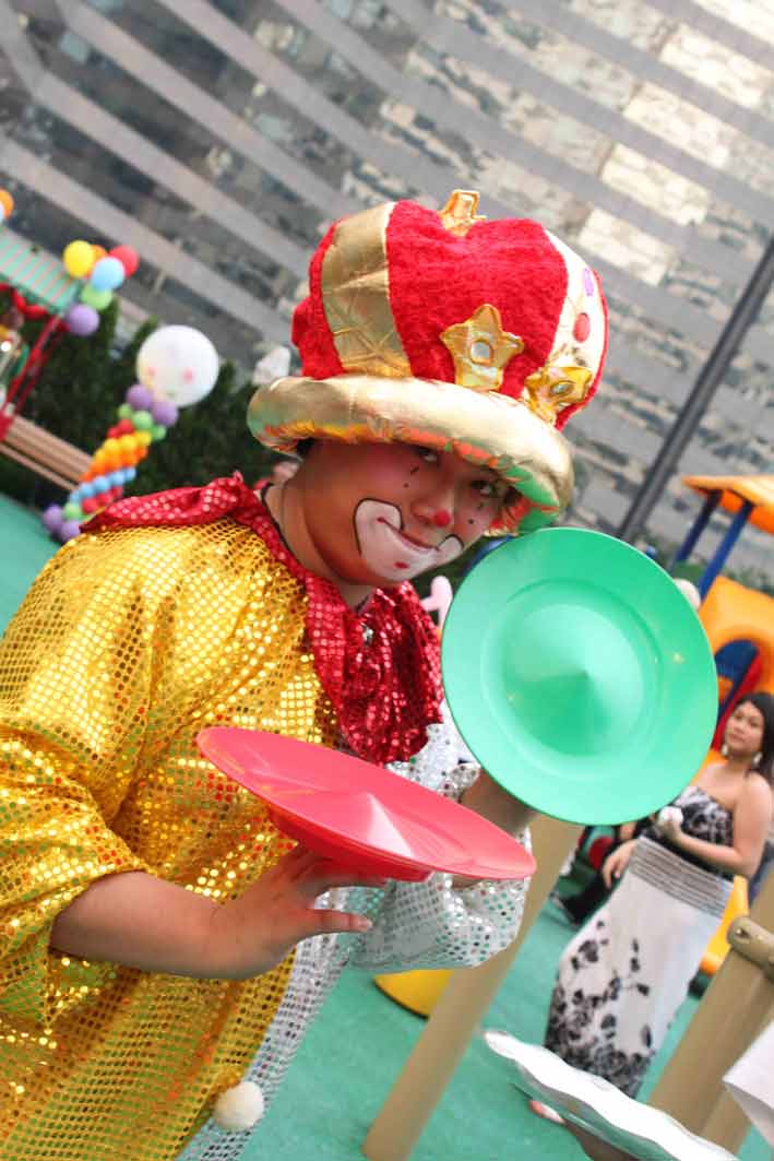 Roving juggling clown in Hong Kong posting with two juggling plates at a corporate family day