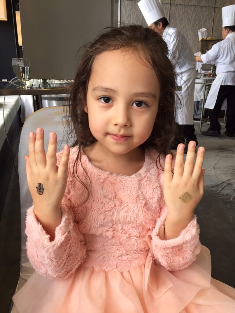 A little girl showing off the tattoos on her hands at a party.