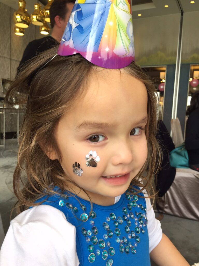 young girl smiling at camera showing her small animal prints henna tattoo
