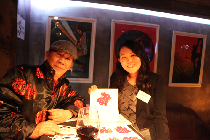 The artist in Hong Kong taking picture with the guest and the rabbit Chinese zodiac cutting at a corporate annual dinner