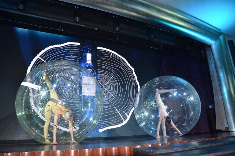 2 acrobats perform in front of blue background