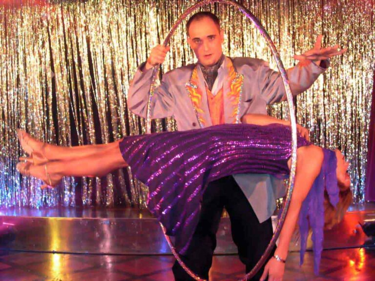 The beautiful lady is levitating and the magician in HK is holding a huge ring to show the audience there is no wires to keep the lady in the middle of the sir at a company function
