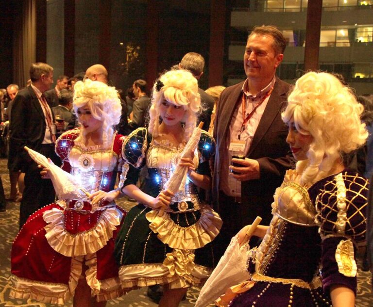 Three  model dancers in period attire taking picture with business men