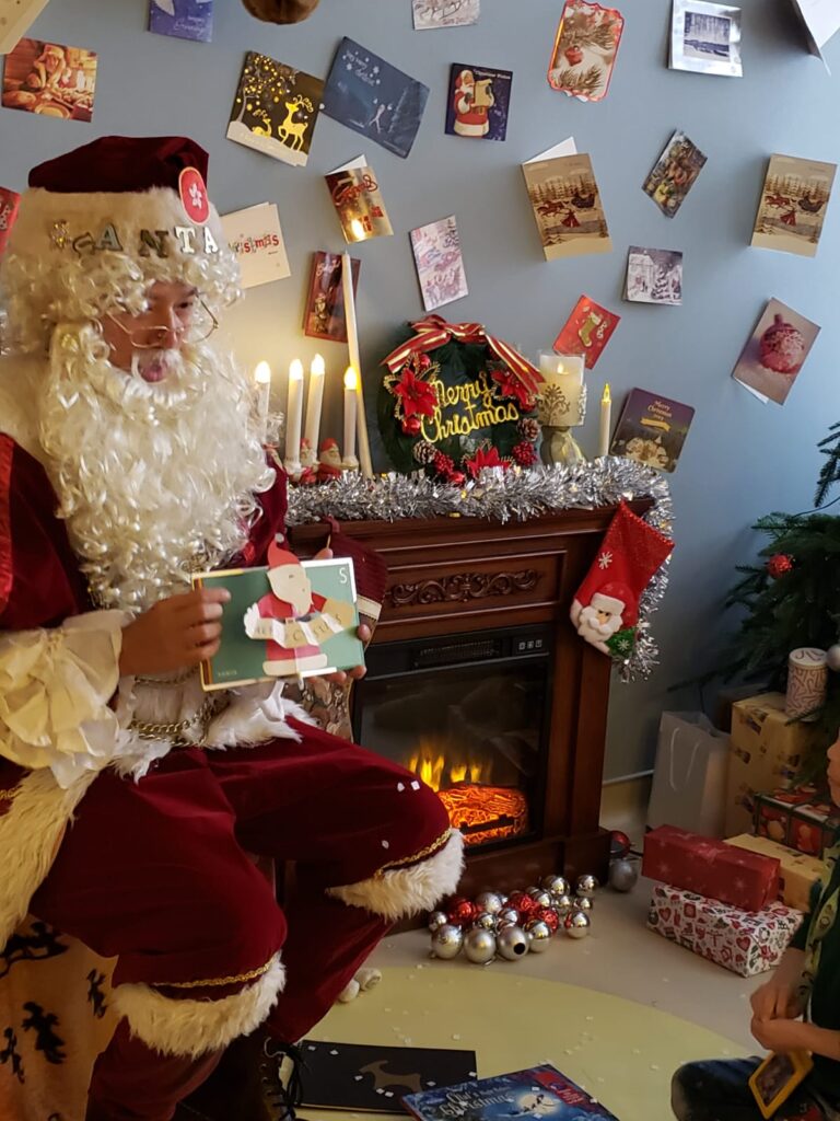 Santa Mario Chinese Santa reading stories to kids in front of a flase fire place in hong kong