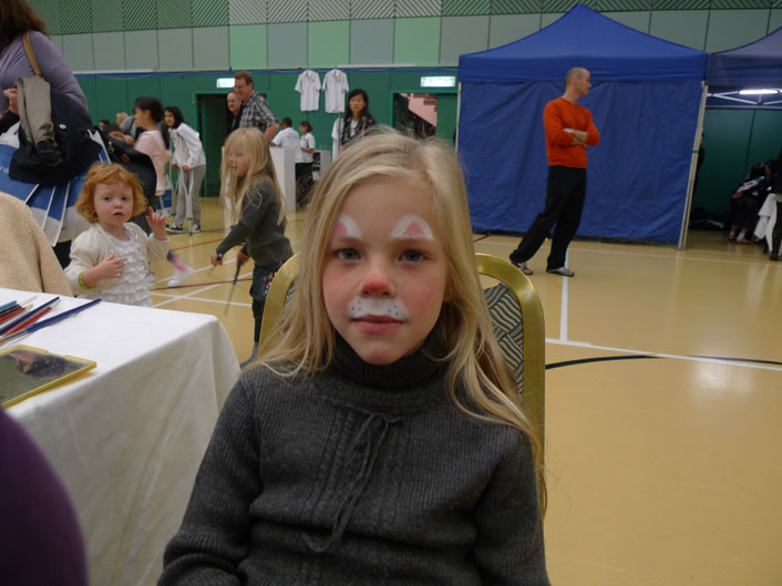 A face painter draw a rabbit face paint for a girl at a corporate Easter event at Hong Kong football club.