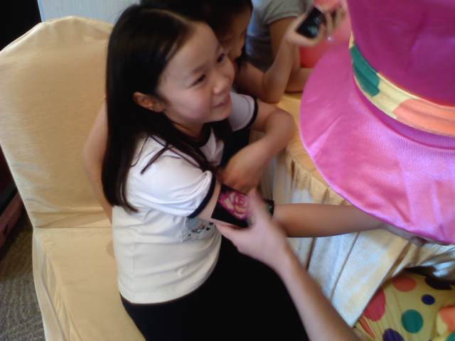 A tattoo artist is using a A rose tattoo template to make a glittering tattoo for a little girl at a corporate kids event.