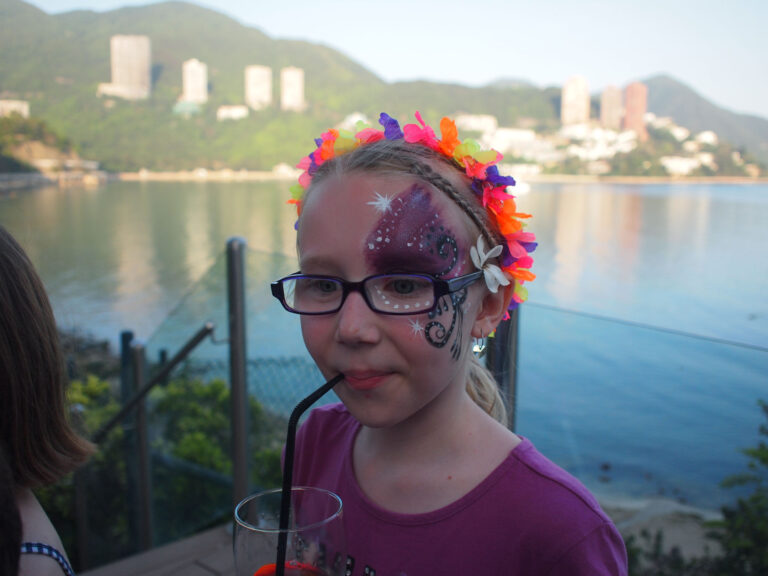 A purple sparkle half-face face paint done by a Hong Kong face painter at a family fun day