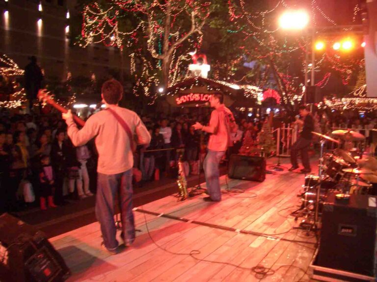 Band onstage at an outdoor event with Santa grotto in background