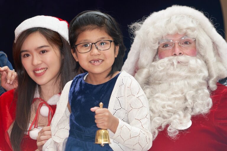 child holding bell in blue top with santa performer from performers hk