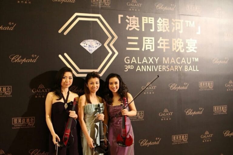 Violinists in Hong Kong taking photo in front of the backdrop before the Galaxy Macau 3RD Anniversary Ball start