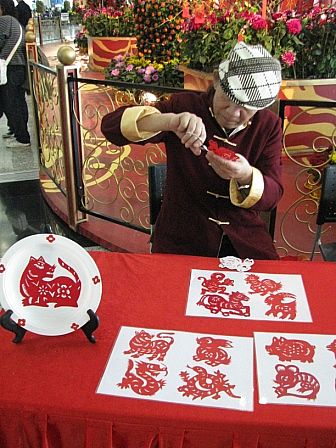 Zodiac paper cutting artist cutting Chinese zodiac animal from a red paper at Hong Kong airport