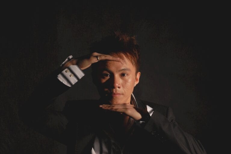 Hong Kong Magician head shot holding his hands in front of his forehead and chin