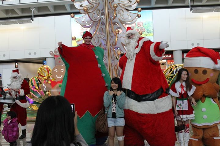 two giant stilt charatcer walk around at christmas hong kong airport in front of a white christmas tree