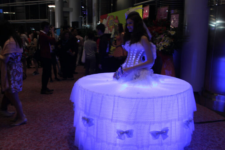 Model dressed in LEd lights and standing in the middle of a table