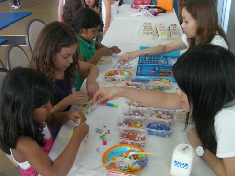 Two staff is assisting the children to decorate their own crafts at a corporate event