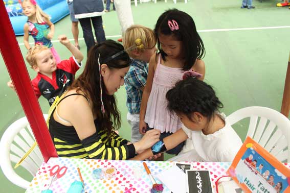 Face painter at a club in Hong Kong painting the arm of a child whilst sitting