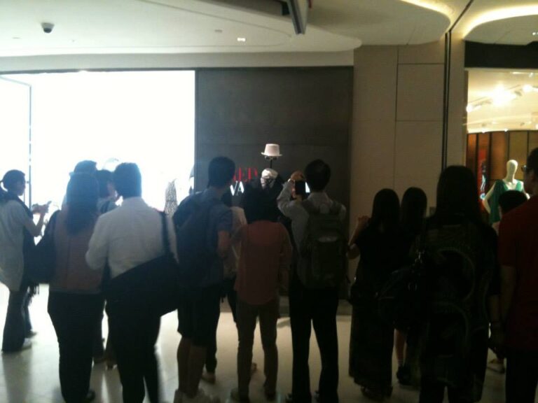 Headless man living state surrounded by large crowd at shopping mall