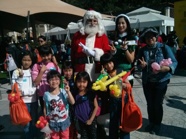 martin santa with santa girl kimmy at an event for children at repulse bay hong kong, kids have balloons and santa and santa girl is smiling