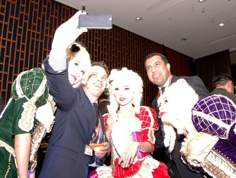 Three performers wearing victorian costume taking picture with guest in a corporate cocktail setting