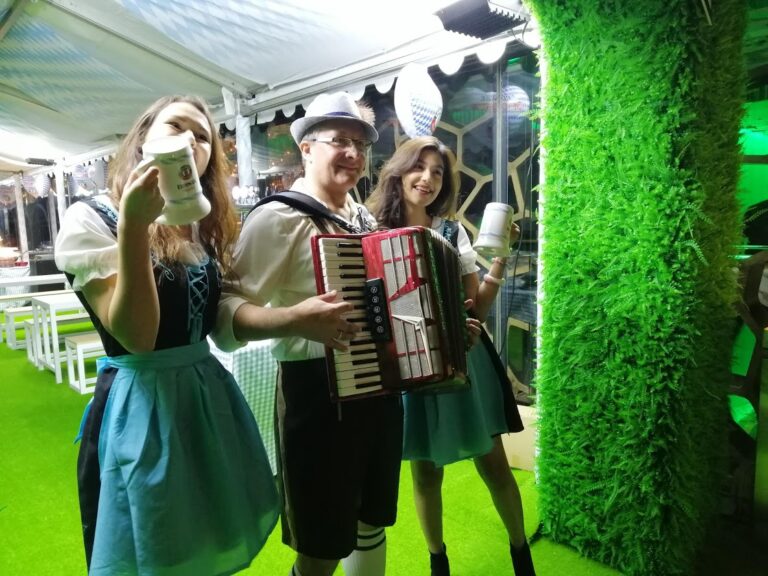 Accordion player in oktoberfest laderhosen with two models in tradtional bavarian beer girl costume at Ritz hong kong