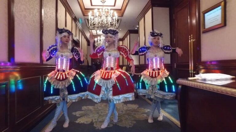 Three dancers wearing victorian era dresses with LED lights