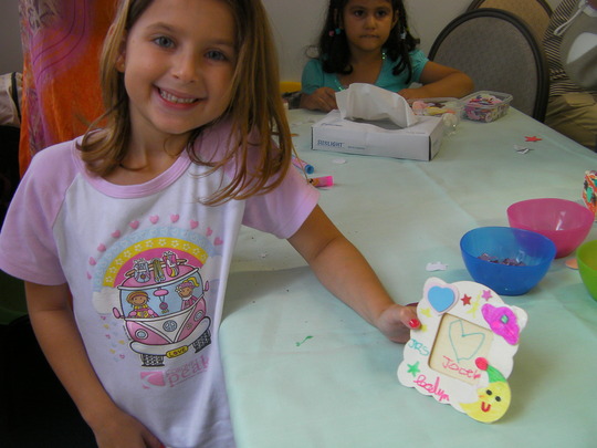 A girl is showing off her own designed photo frame make in a children birthday party