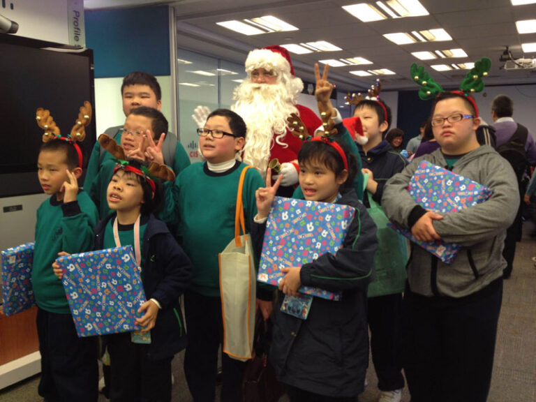 Santa gave presents to nine children in green uniform and taking pictures with them at Xmas school event .