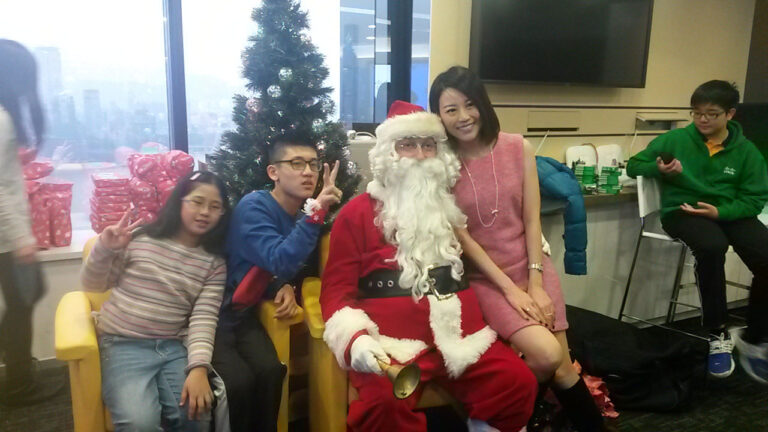 Santa with a lady and two kids taking picture in front of a Christmas tree at a HK Xmas event