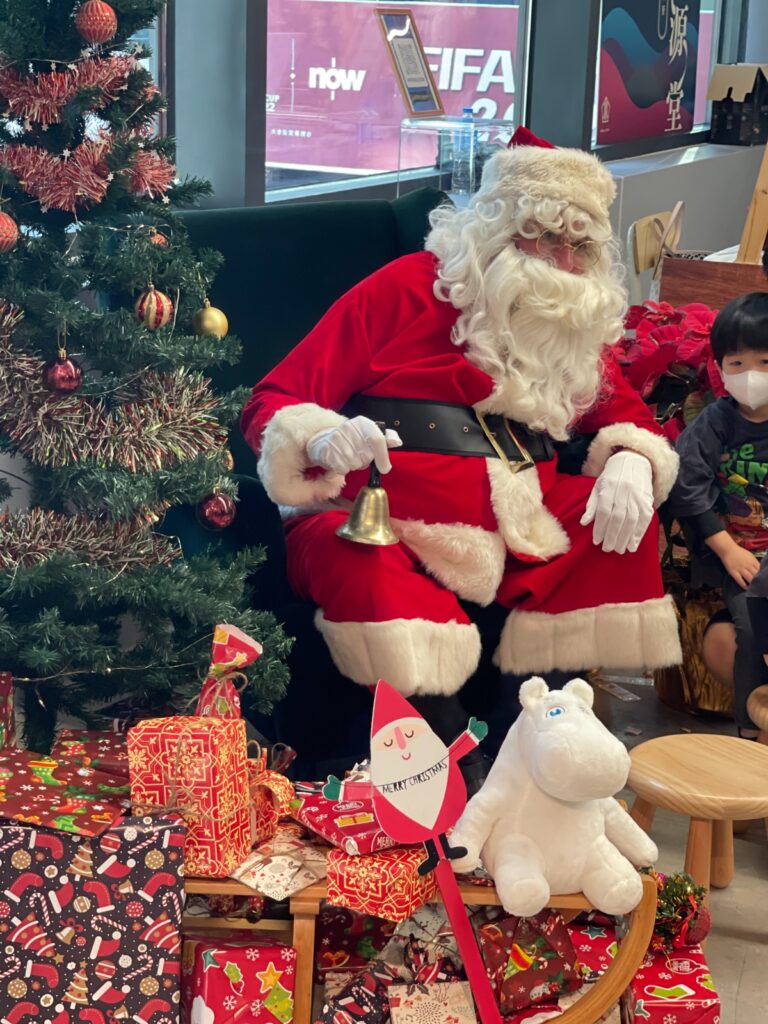 Santa sitting in front of a Christmas tree in Central market Hong kong with a kid next to him