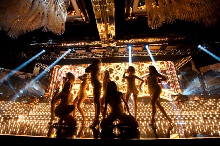 dancers on stage with gold background for crazy horse them event