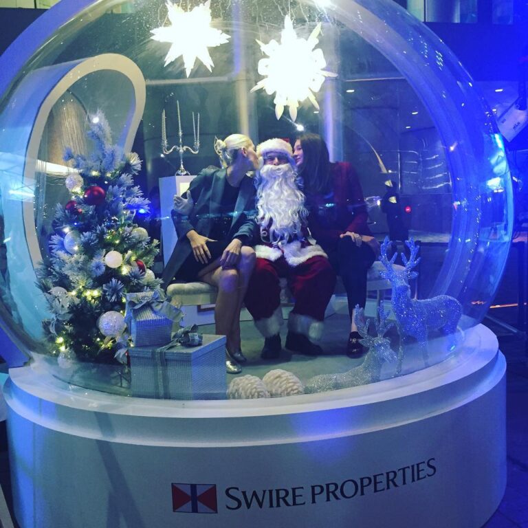 Two girls kissing santa inside a giant snow globe