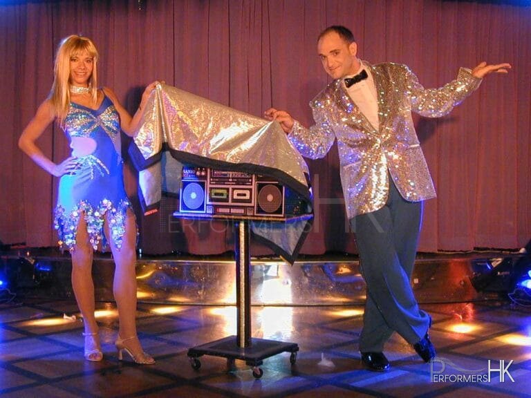 Talented stage magician in Hong Kong and his assistant performing a great show ,they are covering the radio between them with a sliver cloth at a festival function